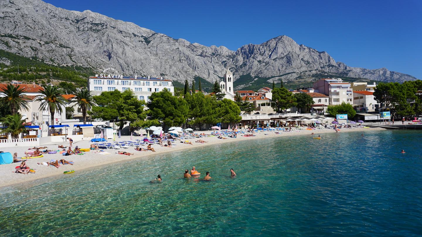 Šljunčana plaža i šetnica u Baškoj Vodi, iza mjesta masiv Biokova