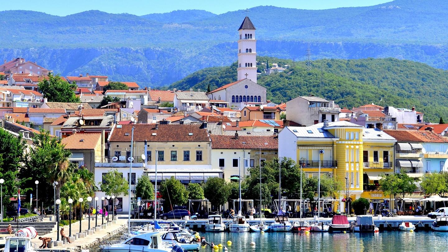 Luka u Crikvenici, obalna šetnica i zvonik pred pošumljenim brdima