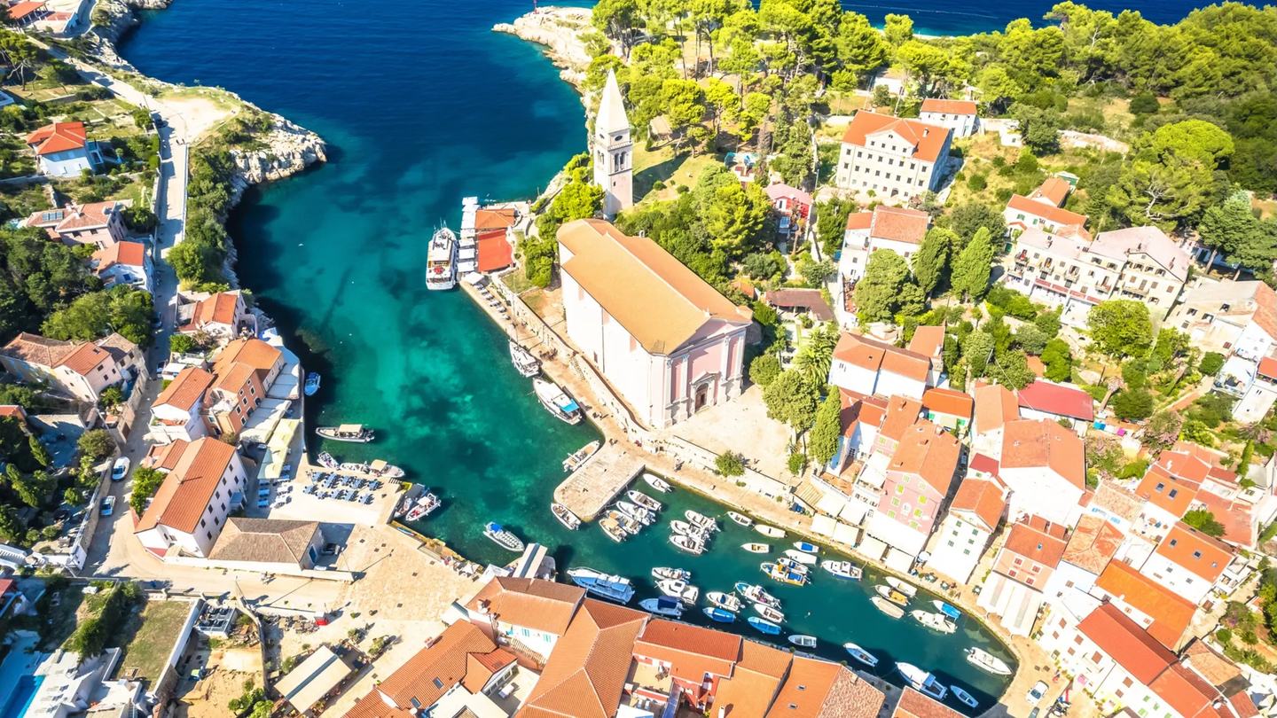 Veli Lošinj iz zraka, crkva iznad uske luke pune malih barki
