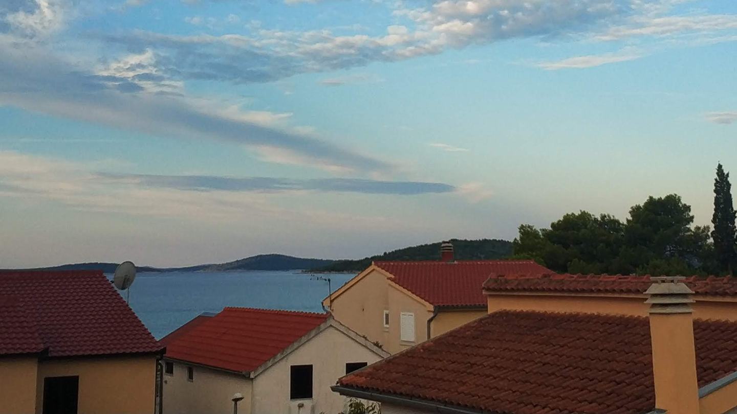 Krovovi od kupe u Podstrani u sumrak, pogled preko Bračkog kanala