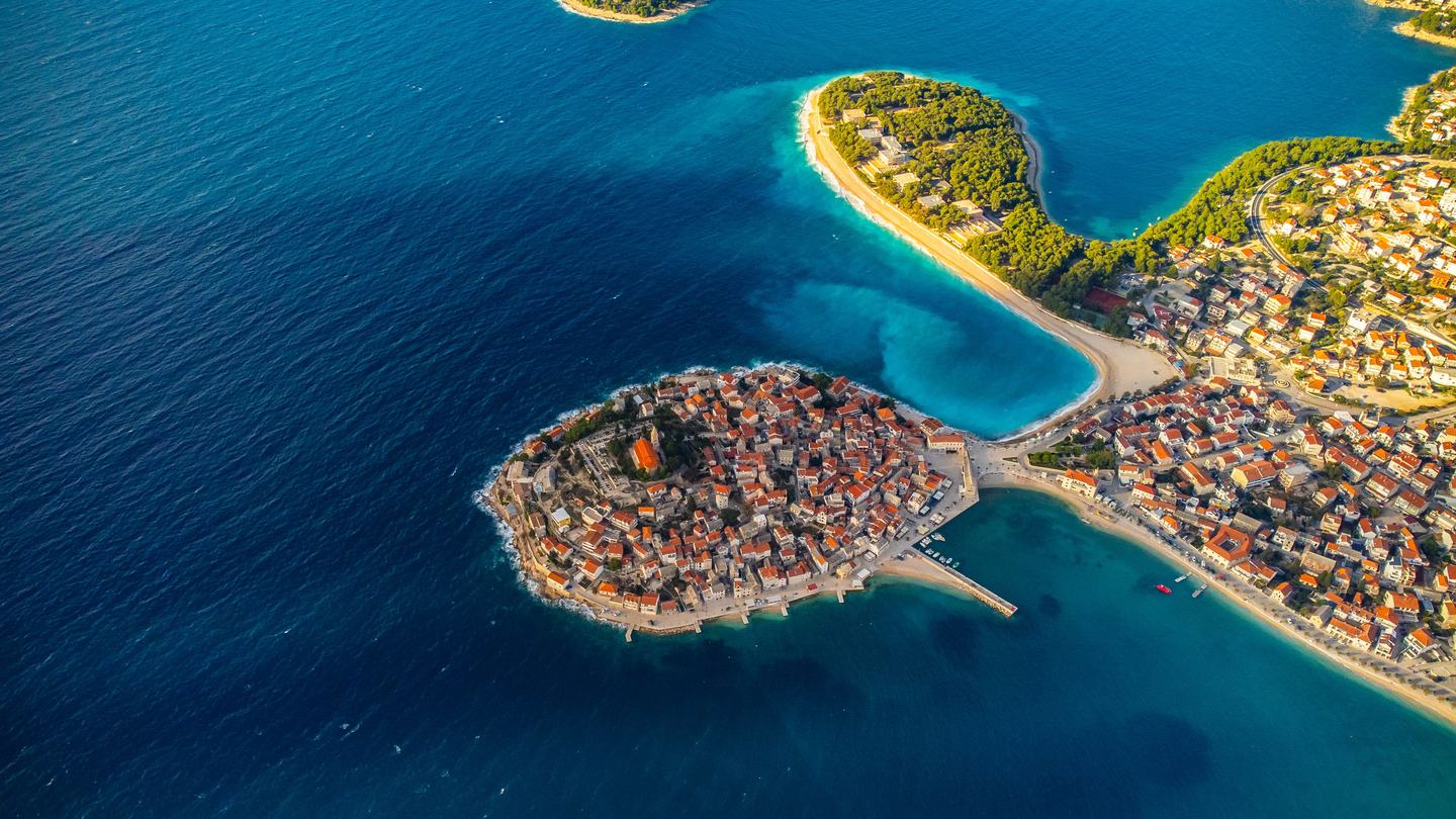 Stara jezgra Primoštena na poluotoku, iz zraka s plažom Raduča uz nju