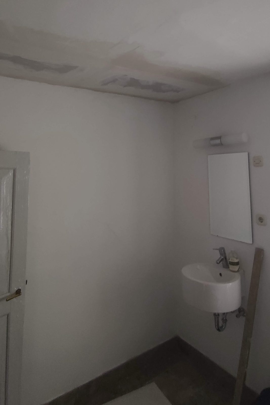 The same bathroom after the repair, ceiling made good, floor clear of debris, basin and mirror back in use